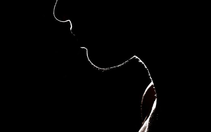Silhouette of a person in a yoga pose against a minimalist, dark background.